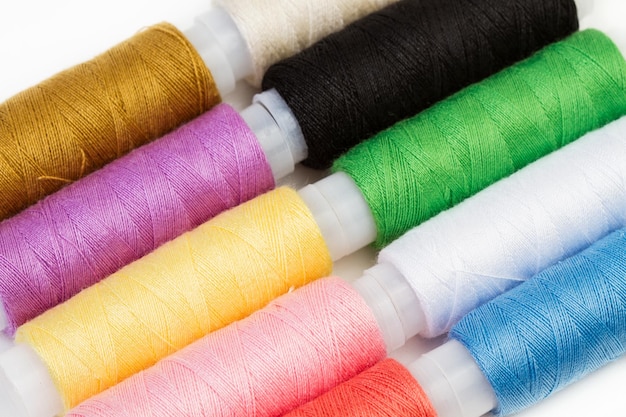 Colored thread spools on a white background in a top view