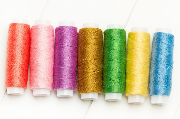 Colored thread spools on a white background in a top view