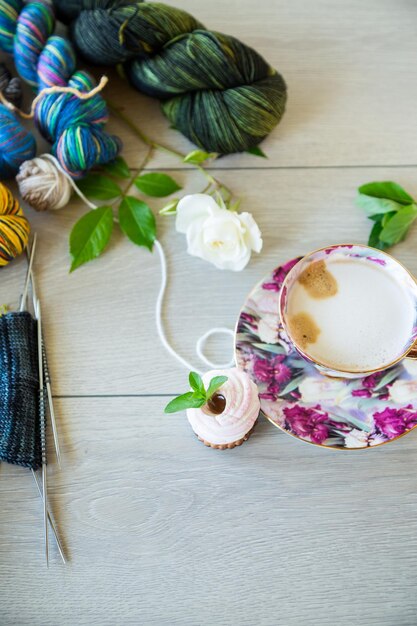 Photo colored threads knitting needles and other items for hand knitting on a light wooden table