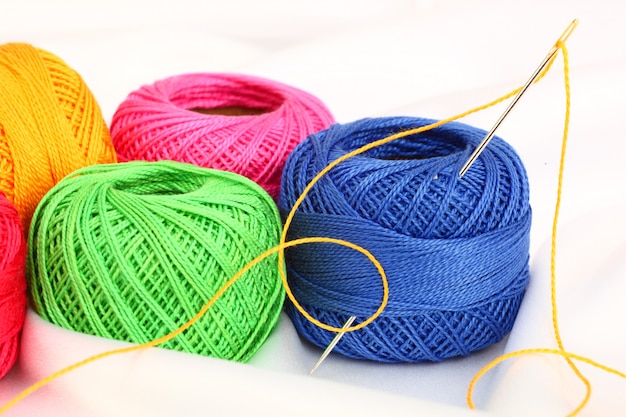 Colored threads with needles for embroidery, on a white background