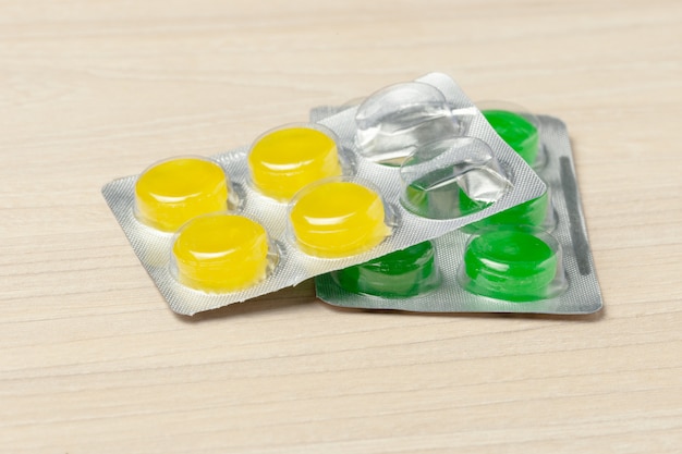 Colored throat pills at wooden table background