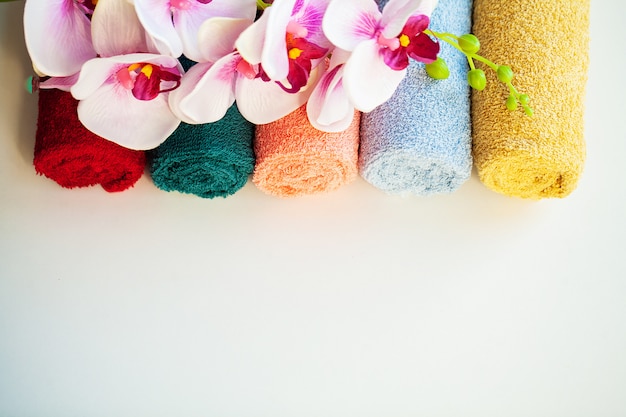 Colored towels and orchid on white table with copy space on bath room background.