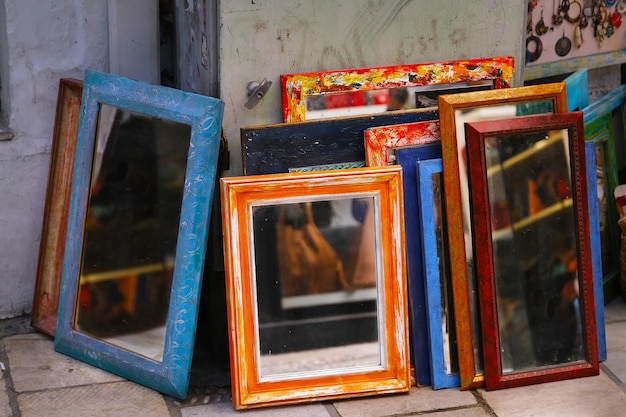 Colored vintage mirrors stand outside at a flea market