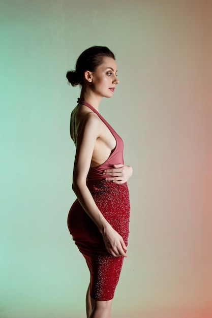 colored wall, neon lights, studio shot. portrait of a young elegant brunette woman