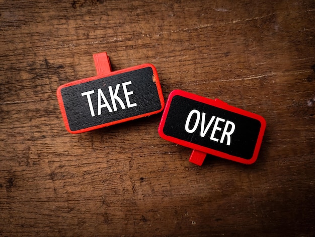 Colored wooden clips with word TAKE OVER on wooden background