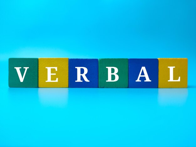 青色の背景に単語 VERBAL と色付きの木製キューブ