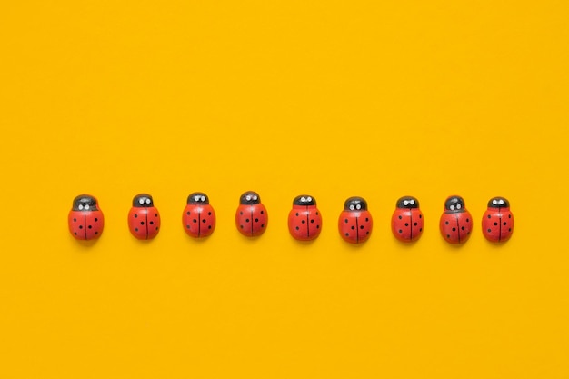 Colored wooden figures in the form of ladybugs on a yellow background