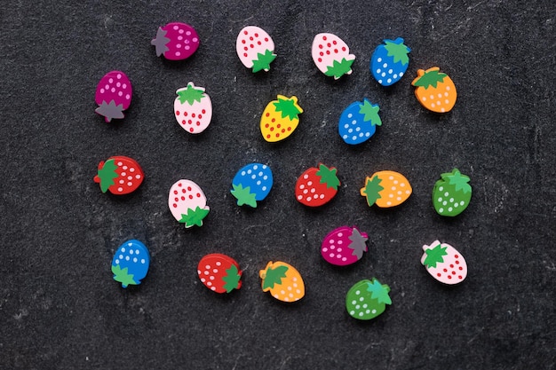 Colored wooden figures in the form of strawberries on a dark background