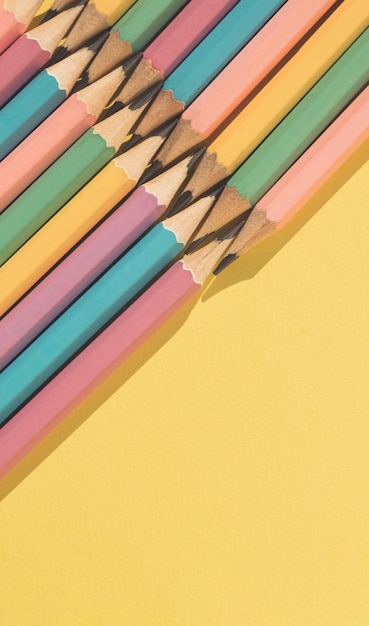 Colored wooden pencils on yellow background Top view with copy space Flat lay Back to school concept