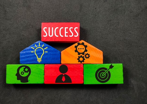 Foto in legno colorato con icone aziendali mirate e il concetto di successo su sfondo nero