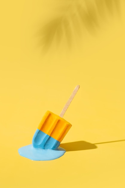 Colored yellow and blue ice cream melts from the hot sun Palm leaves shadow Hot weather concept Vertical format