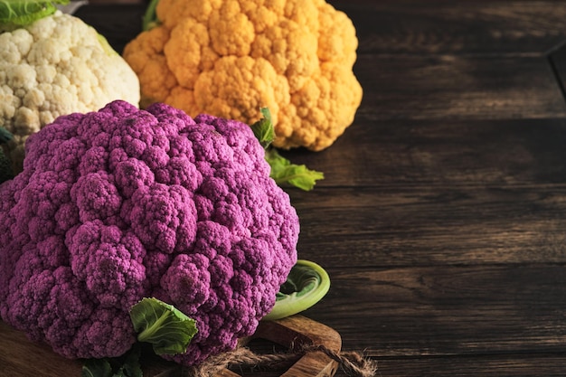 Colorfu cauliflower Various sort of cauliflower on old wooden background Purple yellow white and green color cabbages Broccoli and Romanesco Agricultural harvest Mock up