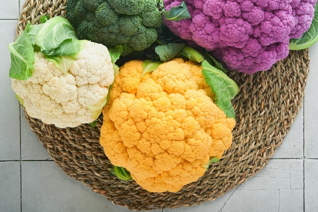 Colorfu cauliflower Various sort of cauliflower on stone tiles gray concrete background Purple yellow white and green color cabbages Broccoli and Romanesco Agricultural harvest Mock up