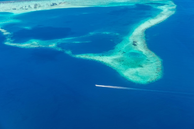 モルディブ環礁とスピードボートで真っ青な海のカラフルな空撮。素晴らしい旅行の背景