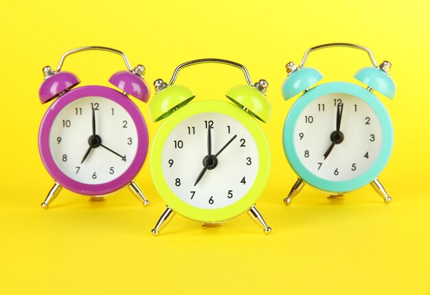 Colorful alarm clock on yellow background