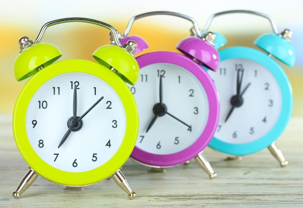 Colorful alarm clocks on table on bright background