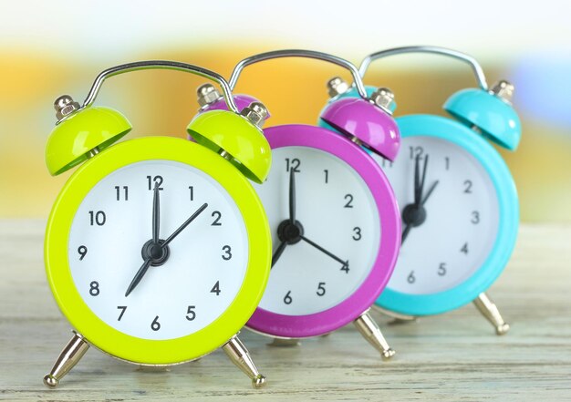 Colorful alarm clocks on table on bright background