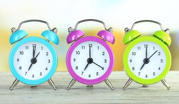 Colorful alarm clocks on table on bright background