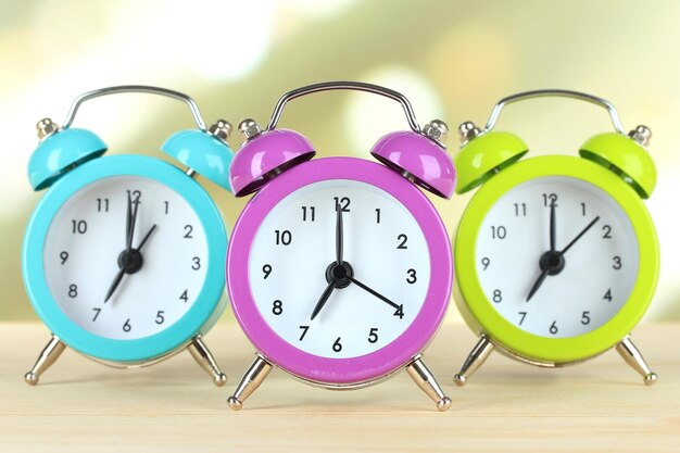 Photo colorful alarm clocks on table on light background