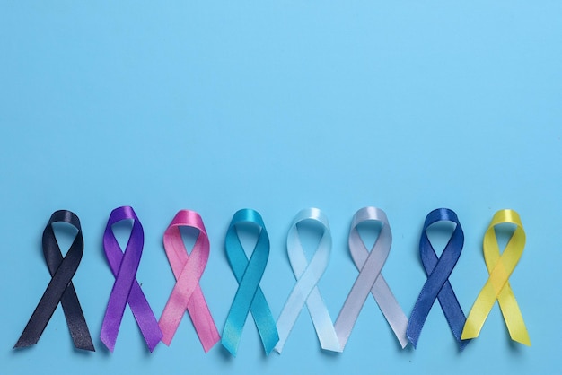 Photo colorful awareness ribbons in line for supporting people living and illness on blue background.