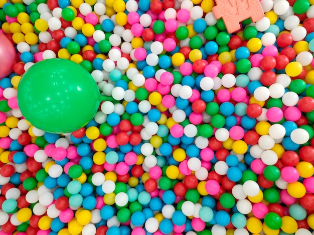 A colorful ball is in a ball pit of colorful balls.