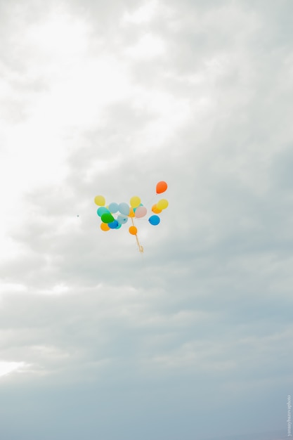 Foto palloncini colorati volano nel cielo. palloncini multicolori in un fascio contro il cielo.