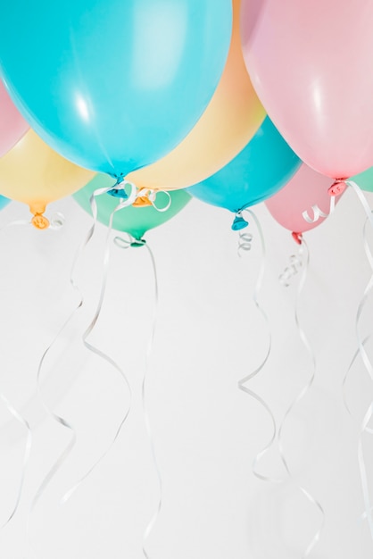 Colorful balloons with ribbons on gray background