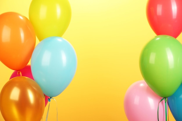 Colorful balloons on yellow background closeup