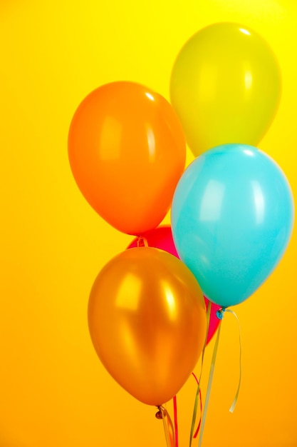 Colorful balloons on yellow background closeup