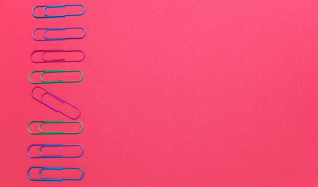 Colorful big paper clips on red color background