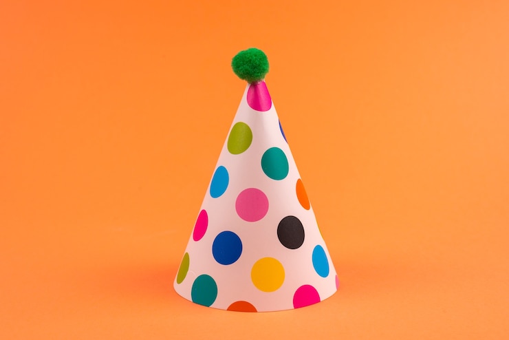 Photo colorful birthday caps on orange background. top view.