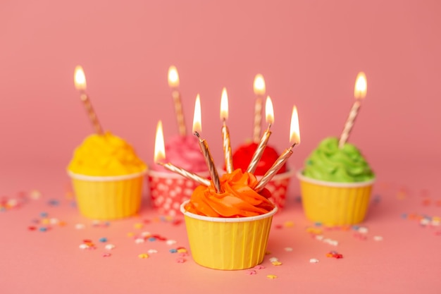 A colorful birthday cupcakes with candle on the pink background Birthday cupcakes