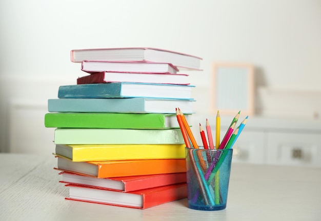 Colorful books and pencil on table in room