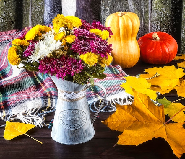 A colorful bouquet of chrysanthemum flowers in a vintage vase pumpkins yellow autumn leaves