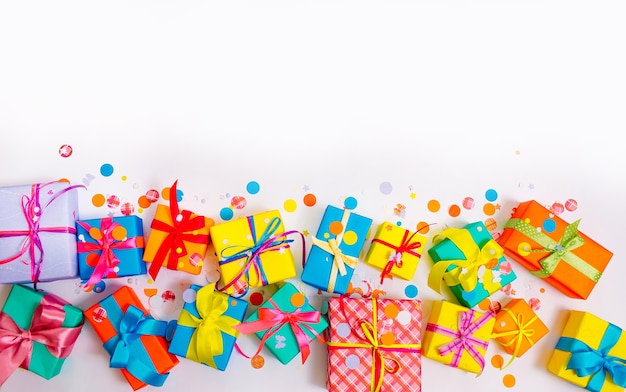 colorful boxes and confetti on a white table with copyspace, top view