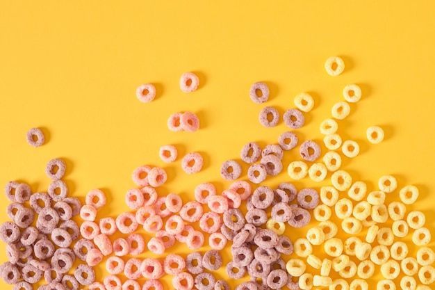 Cereali per la colazione colorati su sfondo giallo vista dall'alto