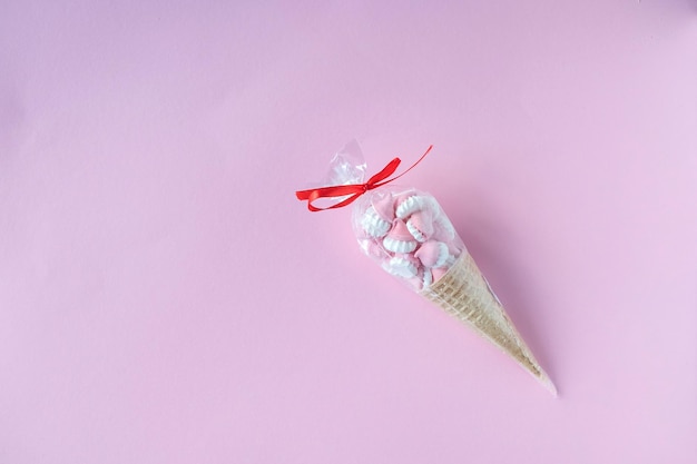 Colorful bright meringues in waffle cookies in transparent packaging lie on a pink background