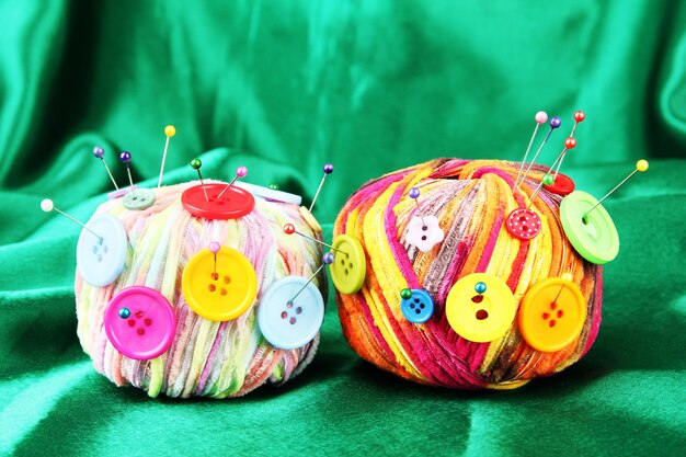 Colorful buttons and multicolor wool balls, on color fabric surface