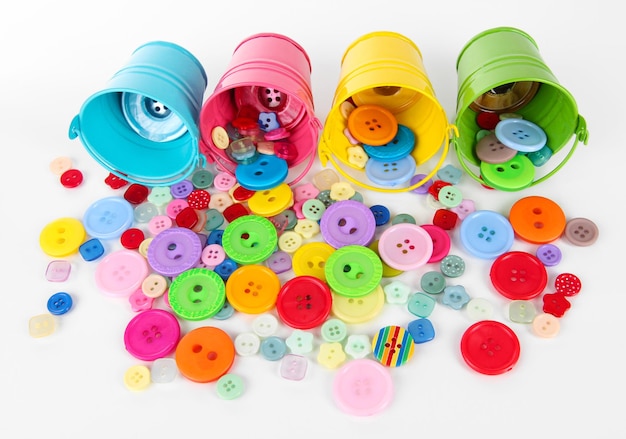 Colorful buttons strewn from buckets isolated on white