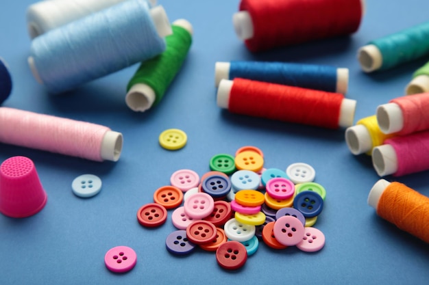 Colorful buttons with colorful thread on dark blue background