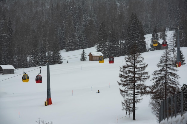 雪の森の上にある冬の山のカラフルなケーブルカー