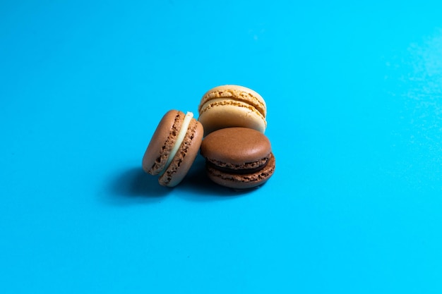 Colorful cake macaron or macaroon on blue background flat lay top view copy space