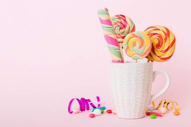 Colorful candies in cup on table on light background background large swirled lollipops creative concept of a jar full of delicious sweets from the candy store