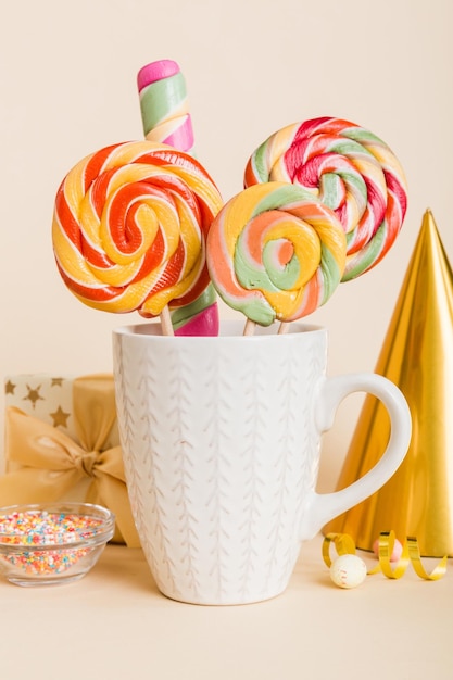 Photo colorful candies in cup on table on light background background large swirled lollipops creative concept of a jar full of delicious sweets from the candy store