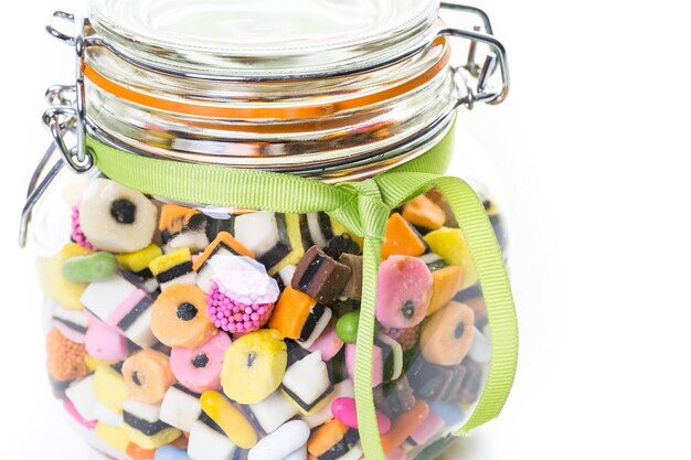 Colorful candies in glass candy jar on a white background.