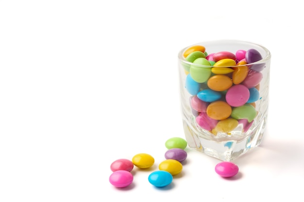 Colorful candies in glass on white background