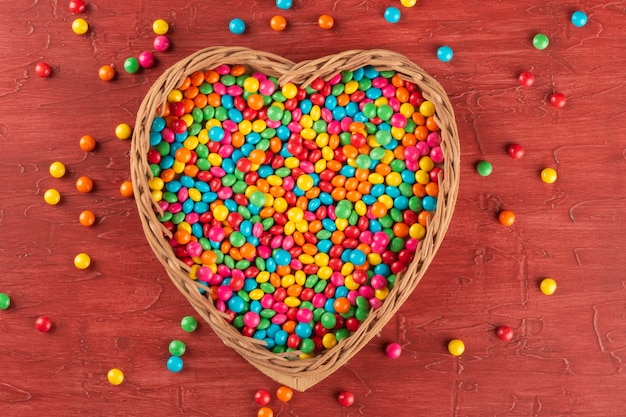 Colorful candies inside the heart with red background