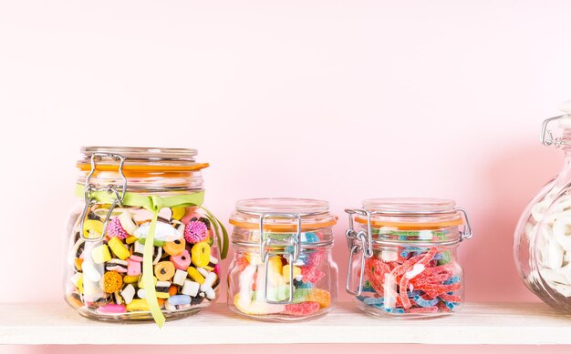 Photo colorful candies in jars on shelf.