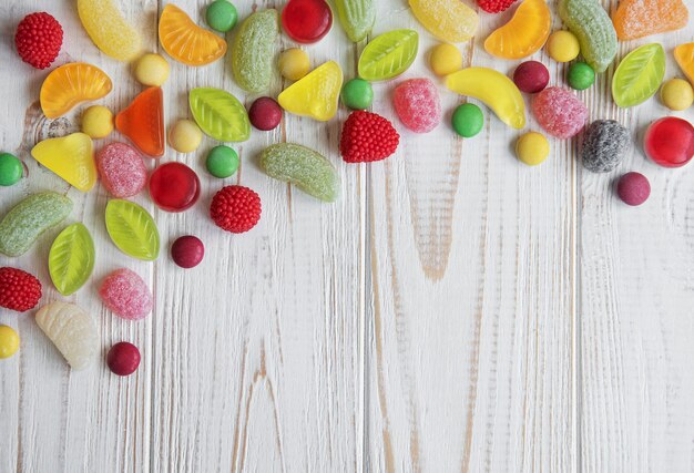 Colorful candies, jelly and marmalade on white wooden surface with copy space