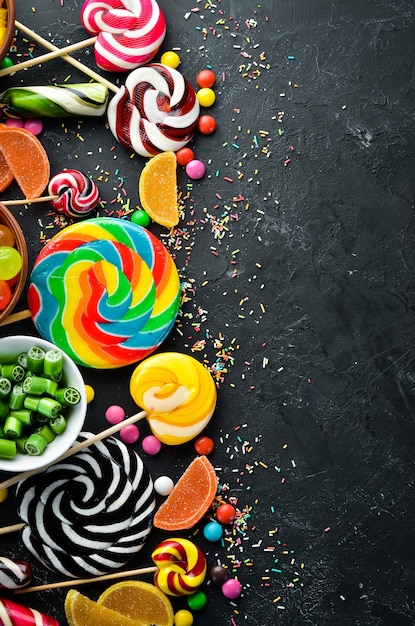 Colorful candies and lollipops On a black stone background Top view free copying space